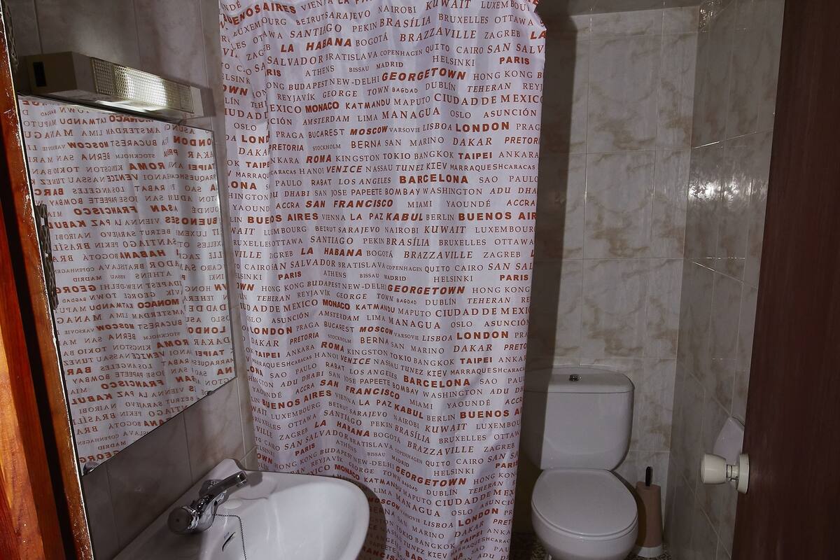A bathroom with a shower curtain, sink, and toilet.