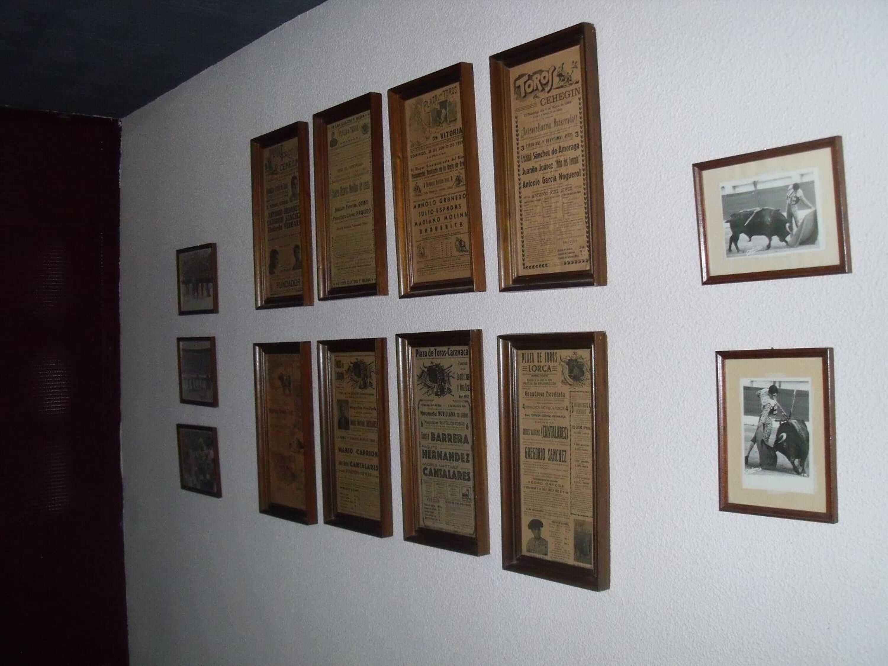 Een muur met meerdere ingekaderde documenten en foto's.