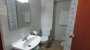A small bathroom with a white sink, toilet, and mirror.
