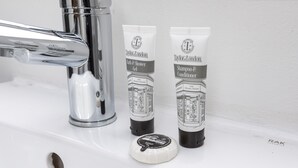 Een wastafel met twee tubes Taylor London Bath & Shower Gel en Shampoo & Conditioner, en een zeepstaaf.