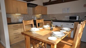 A kitchen with wooden cabinets, a dining table set for four, and a microwave.
