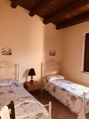A bedroom with two single beds, a nightstand with a lamp, and two wall-mounted pictures. - Agriturismo Ilardo (Collesano)