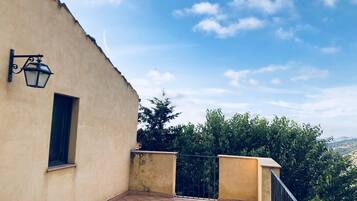 Un balcone con pavimento piastrellato, una piccola finestra e un faretto a parete.