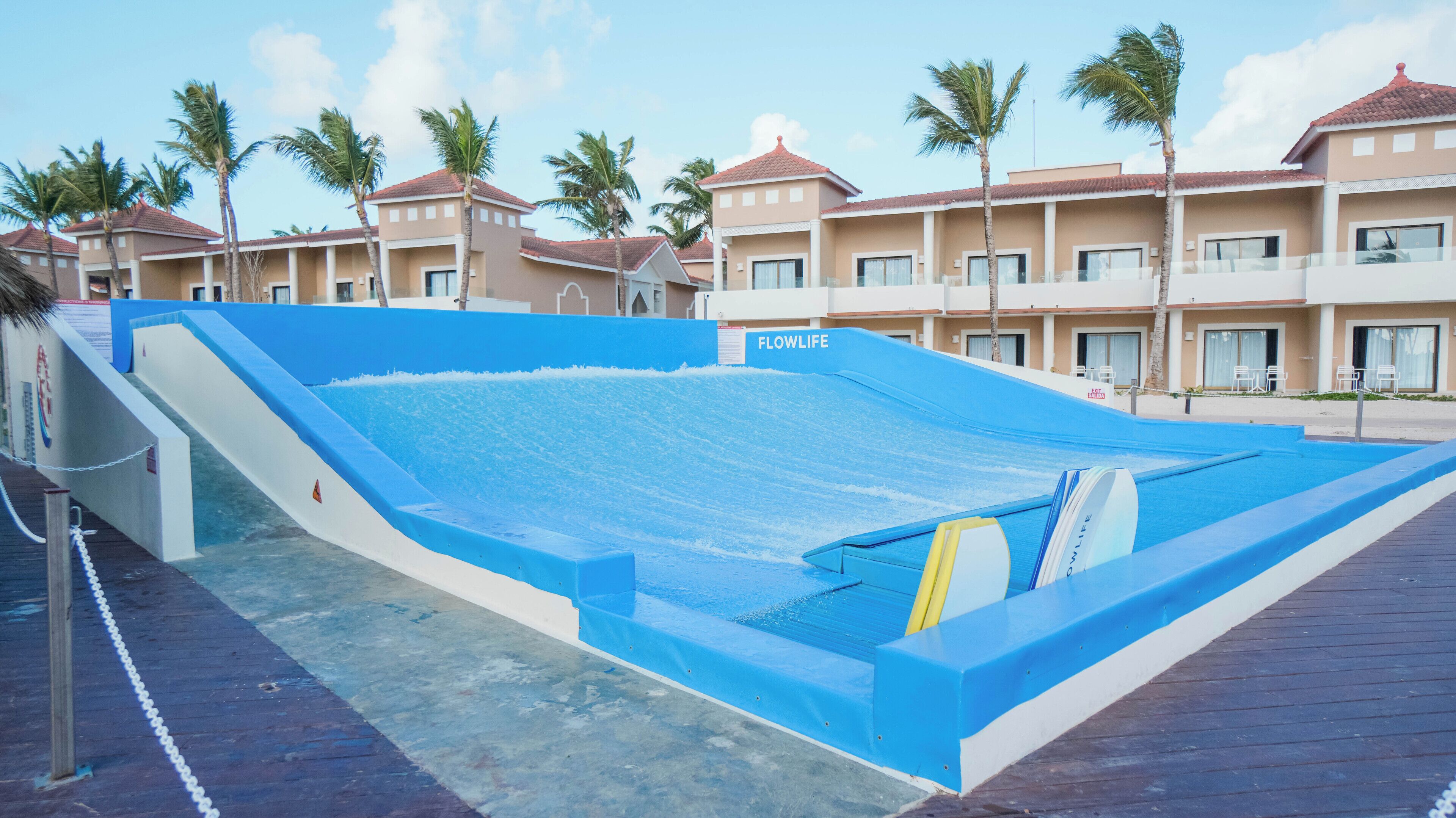 A swimming pool with a blue border, a slide, and a sign that reads 'FLOWLIFE.'
