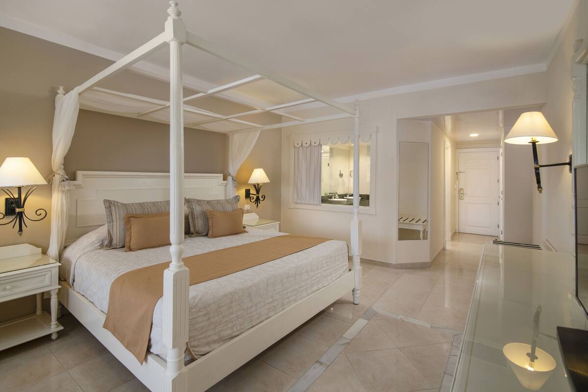 A four-poster bed with a canopy, bedside tables, and lamps.