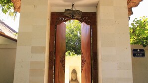 Une porte avec un cadre en bois et une statue de pierre en arrière-plan.