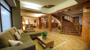 A spacious lobby with a modern staircase, comfortable seating, and a reception area. - Eden Grand Resort (Predeal)