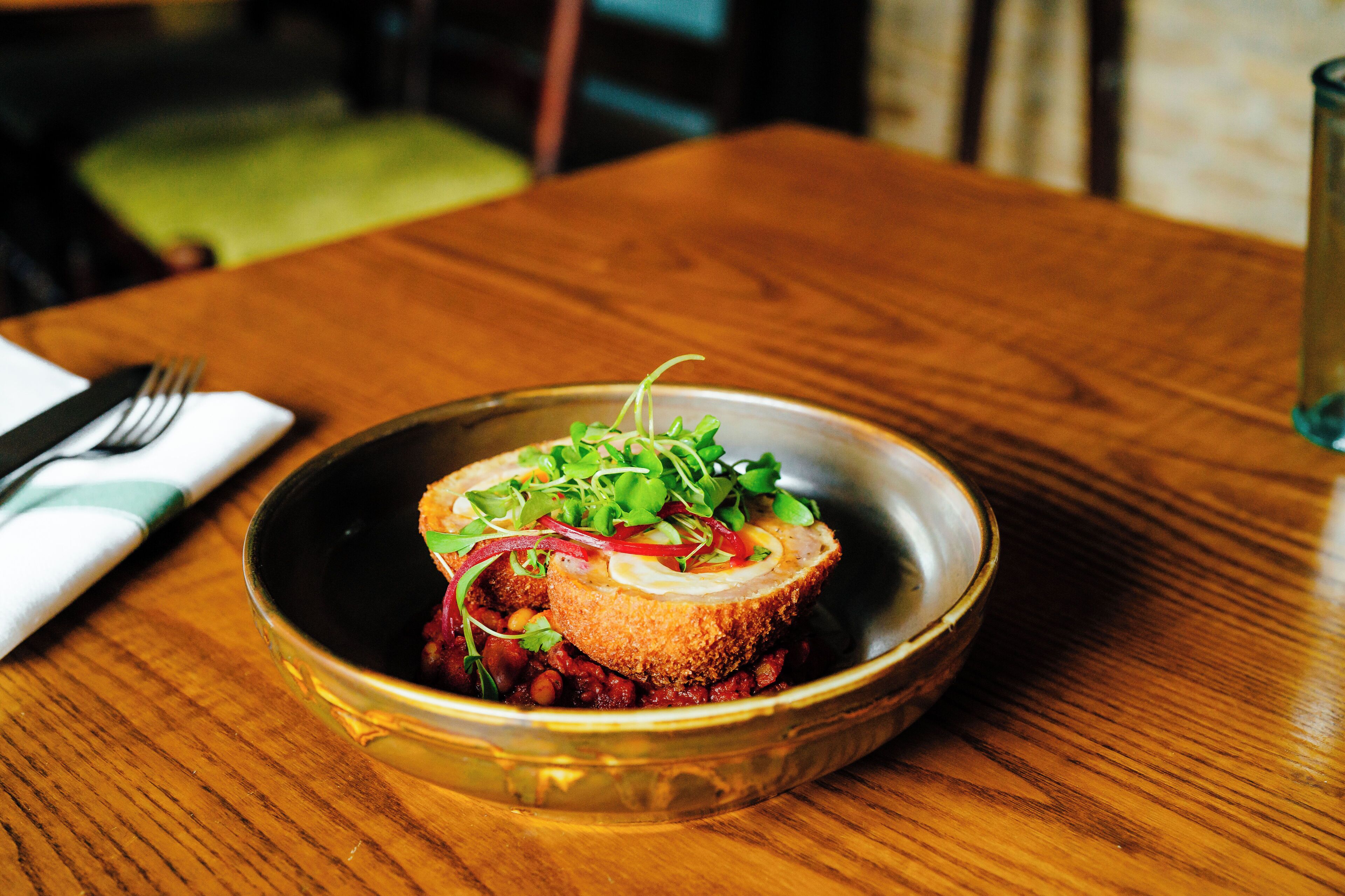 Un plato con vegetales verdes y rojos sobre una mesa de madera.