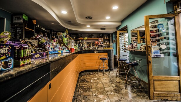 A bar area with a curved counter, stools, and various items on display. - Hotel la Spagnola (Amantea)