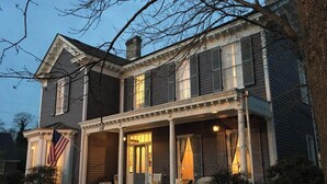 A two-story house with a porch, a flag, and a chimney. - The Wynne House Inn (Holly Springs)