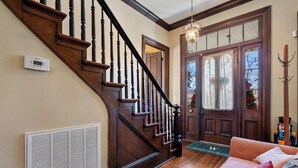 A wooden staircase with a thermostat and a vent on the wall. - The Wynne House Inn (Holly Springs)