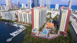 A high-rise hotel with multiple floors, a rooftop pool, and a marina with boats. - Intracostal Sunny Isles (Sunny Isles Beach)