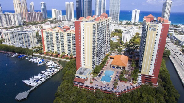 A high-rise hotel with multiple floors, a rooftop pool, and a marina with boats. - Intracostal Sunny Isles (Sunny Isles Beach)