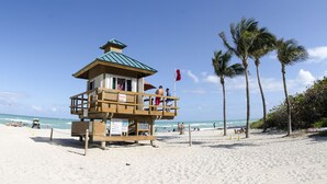 A lifeguard tower on a beach with a clear view of the ocean, palm trees, and a pier in the background. - Intracostal Sunny Isles (Sunny Isles Beach)