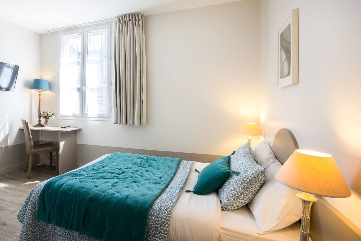 Une chambre à coucher avec un lit, des lampes de chevet, un bureau et une chaise.