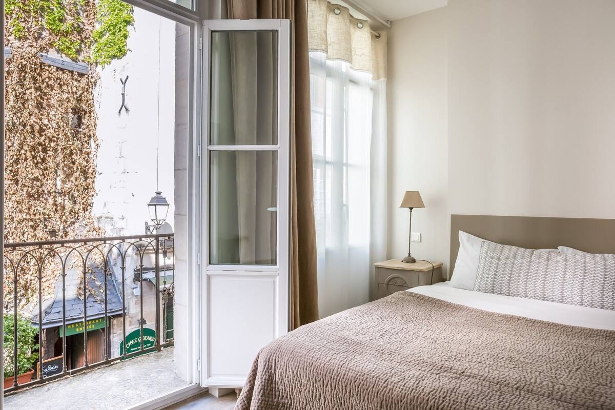 Une chambre avec un lit, une table de chevet, une lampe et une vue sur un restaurant et un espace extérieur.