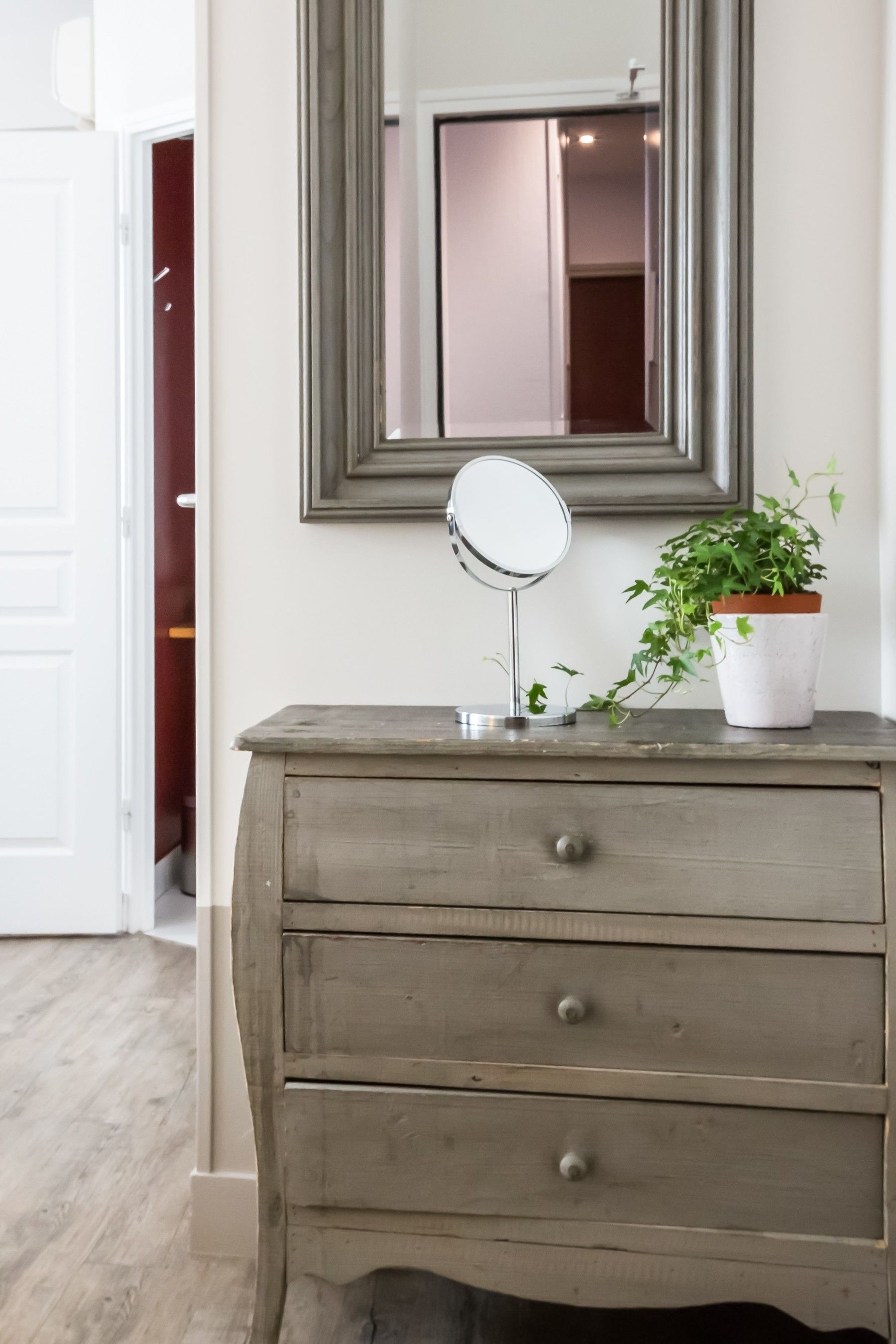 A wooden dresser with a mirror and a potted plant.