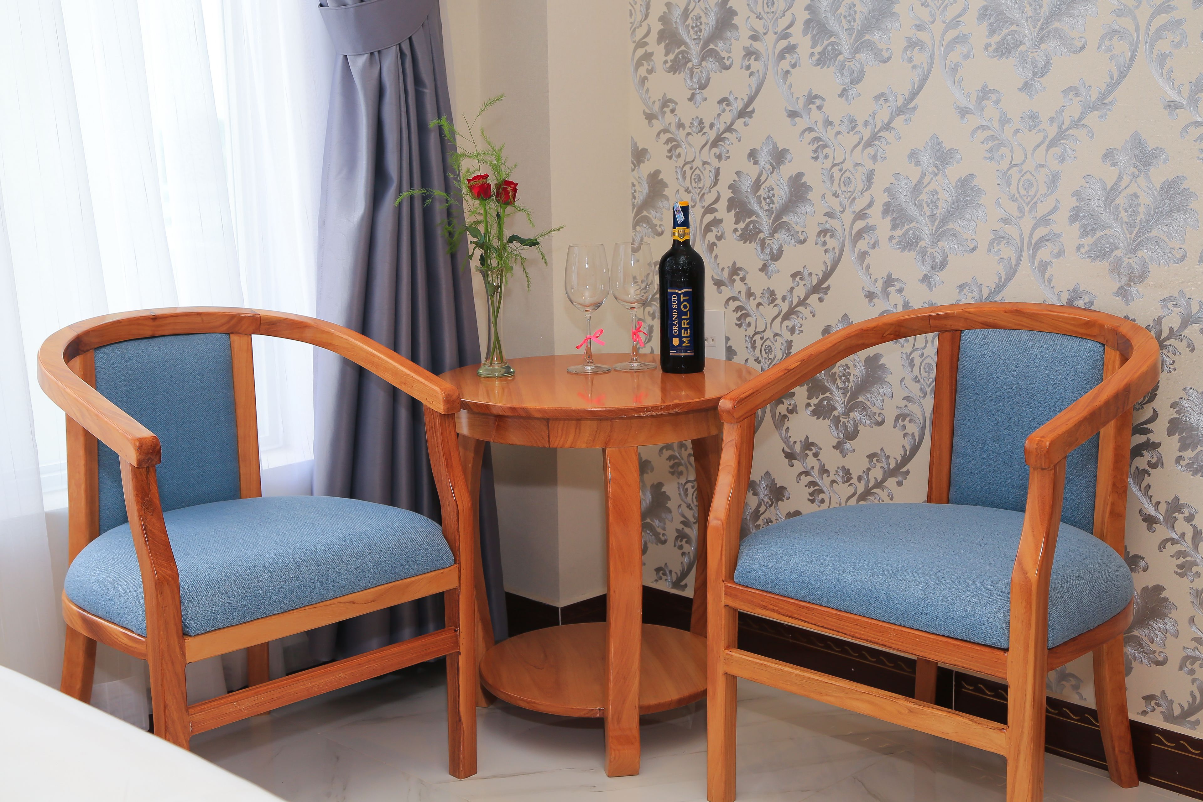 Una mesa de madera con dos sillas, una botella de vino y un jarrón con flores.