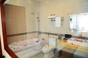 A modern bathroom with a bathtub, toilet, and shower.