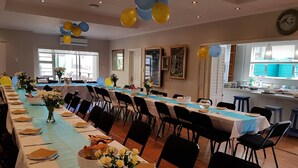 A long dining table with chairs, balloons, and vases of flowers. - Goulden Street Guest House (East London)