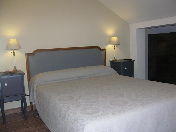 A neatly made bed with a wooden headboard in a room with two bedside tables, each with a lamp.