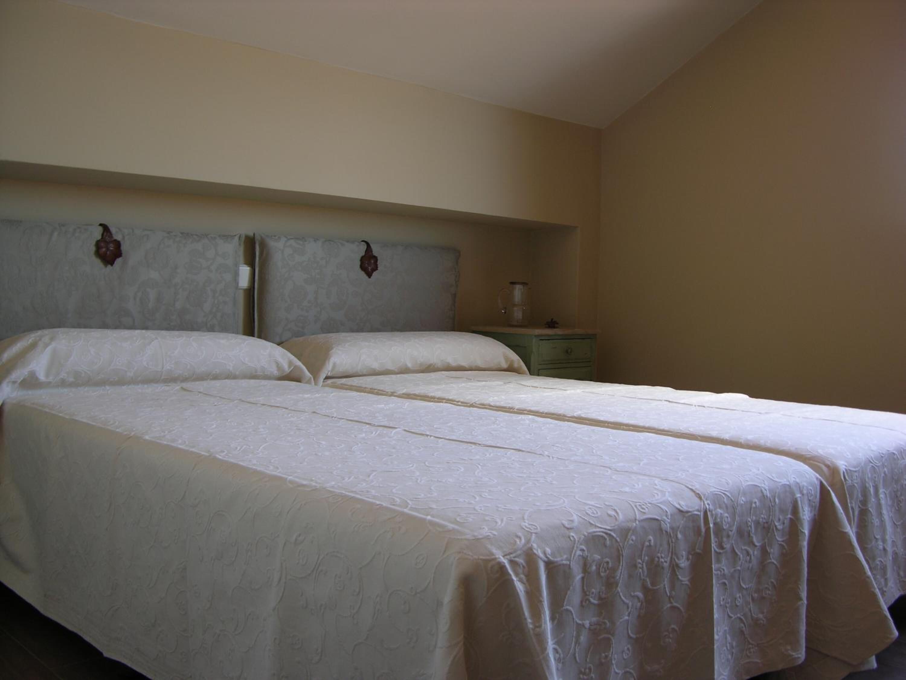 A double bed with a headboard, a bedside table with a lamp, and a wall-mounted clock.