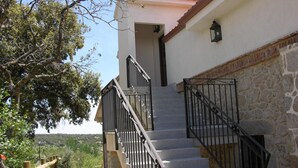 A staircase with stone steps and black railings leading to a white building with a red-tiled roof.