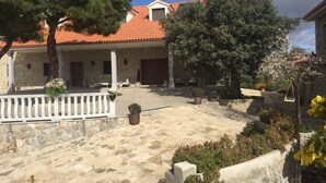 A stone building with a red-tiled roof, a covered patio area with outdoor seating, and a stone courtyard.