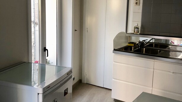 A compact kitchen with white cabinets, a stainless steel sink, and a Bosch refrigerator. - Exclusive Flats In Brussels - Olives (Brussels)