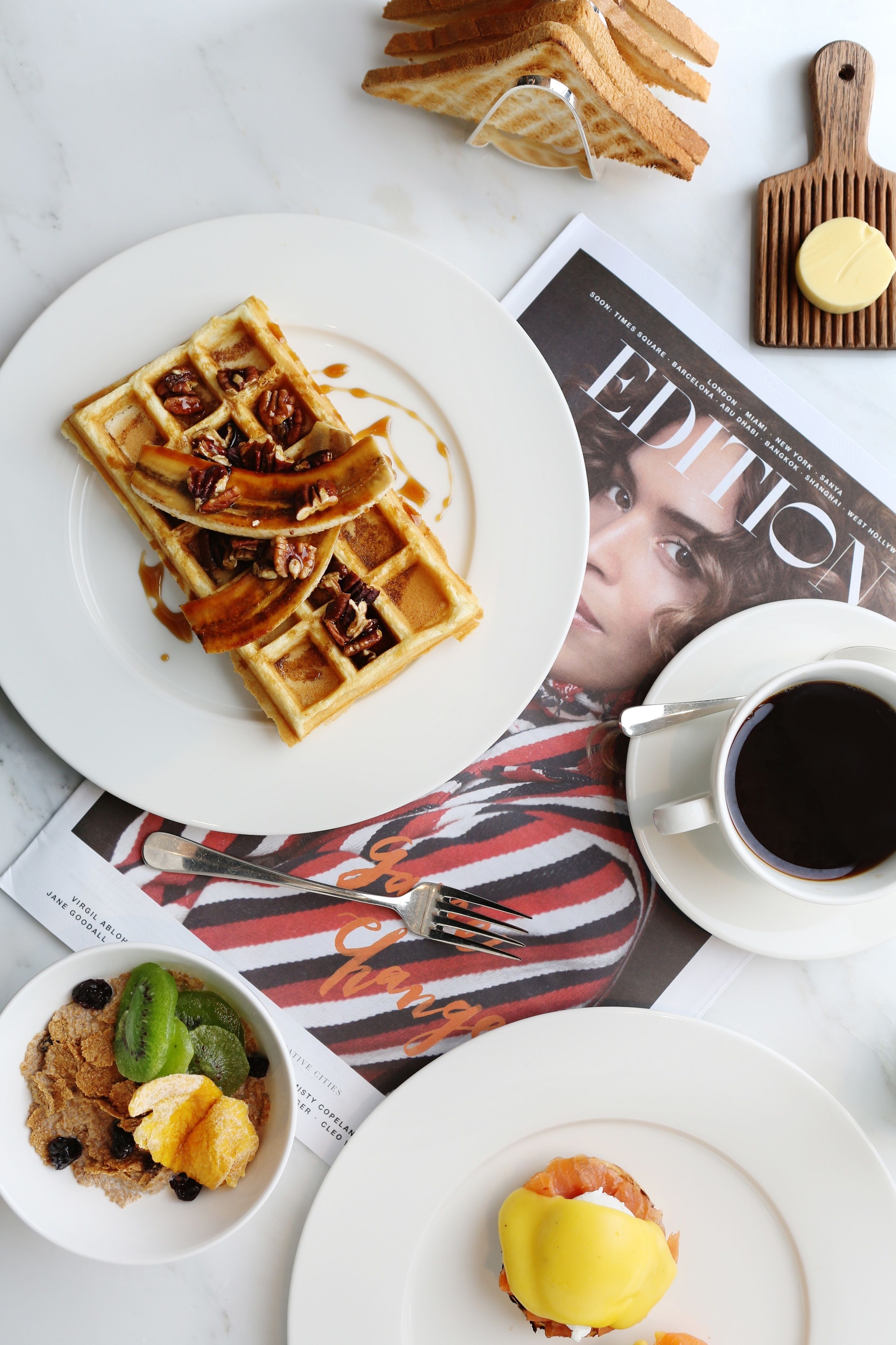 Un esmorzar amb gofres, una tassa de cafè i una revista.