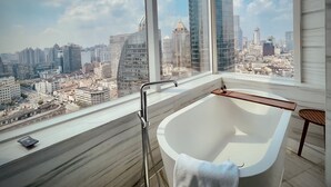 A modern bathroom with a freestanding bathtub, a window overlooking a cityscape with high-rise buildings. - The Shanghai EDITION (Shanghai)
