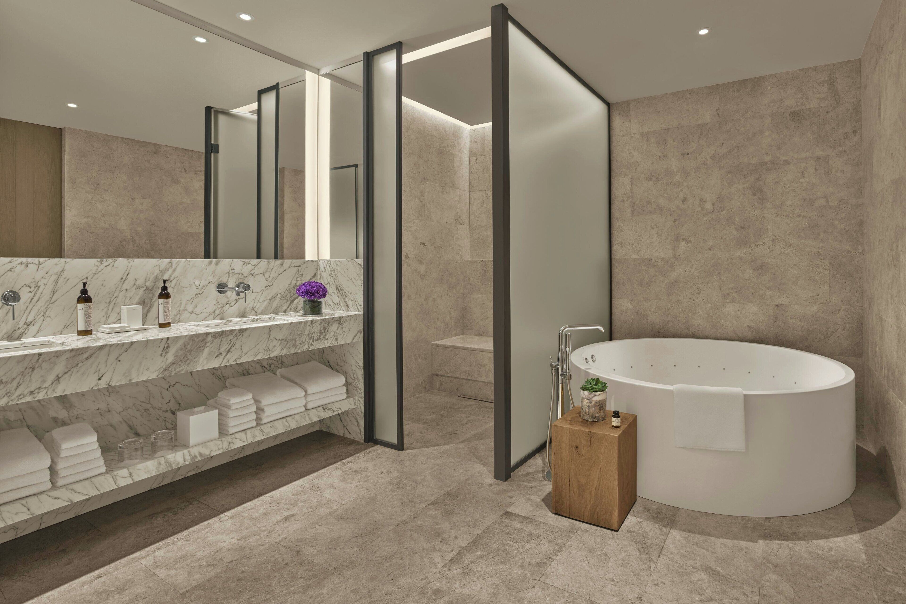 Un baño moderno con tocador de mármol, una bañera independiente y un espejo grande.