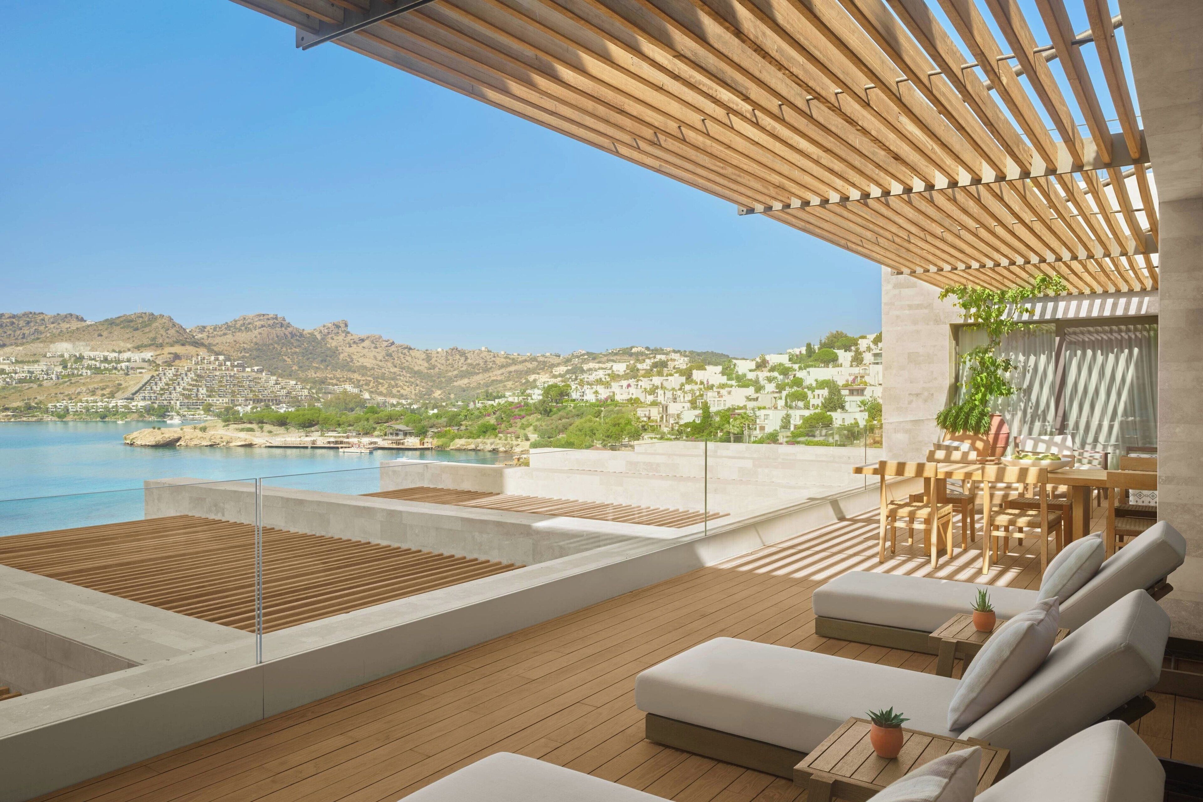 A rooftop terrace with a pool, outdoor seating, and a view of the city and hills.
