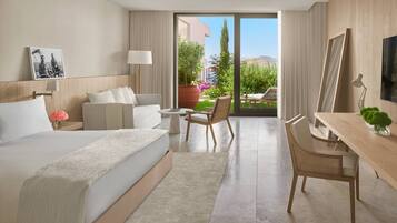 Habitación de hotel con cama, escritorio, silla, una mesita y vistas al exterior.