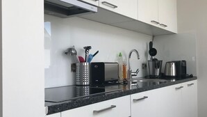 Eine moderne Küche mit weißen Schränken, einer schwarzen Arbeitsplatte, Edelstahlgeräten und einem eingebauten Backofen.