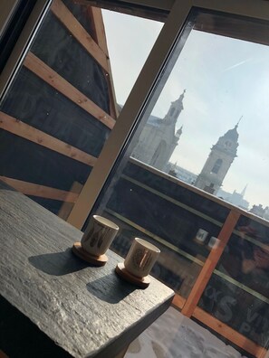 A wooden table with two cups, a window with a view of a tower. - Exclusive Flats Sainte-Catherine Terrace (Brussels)