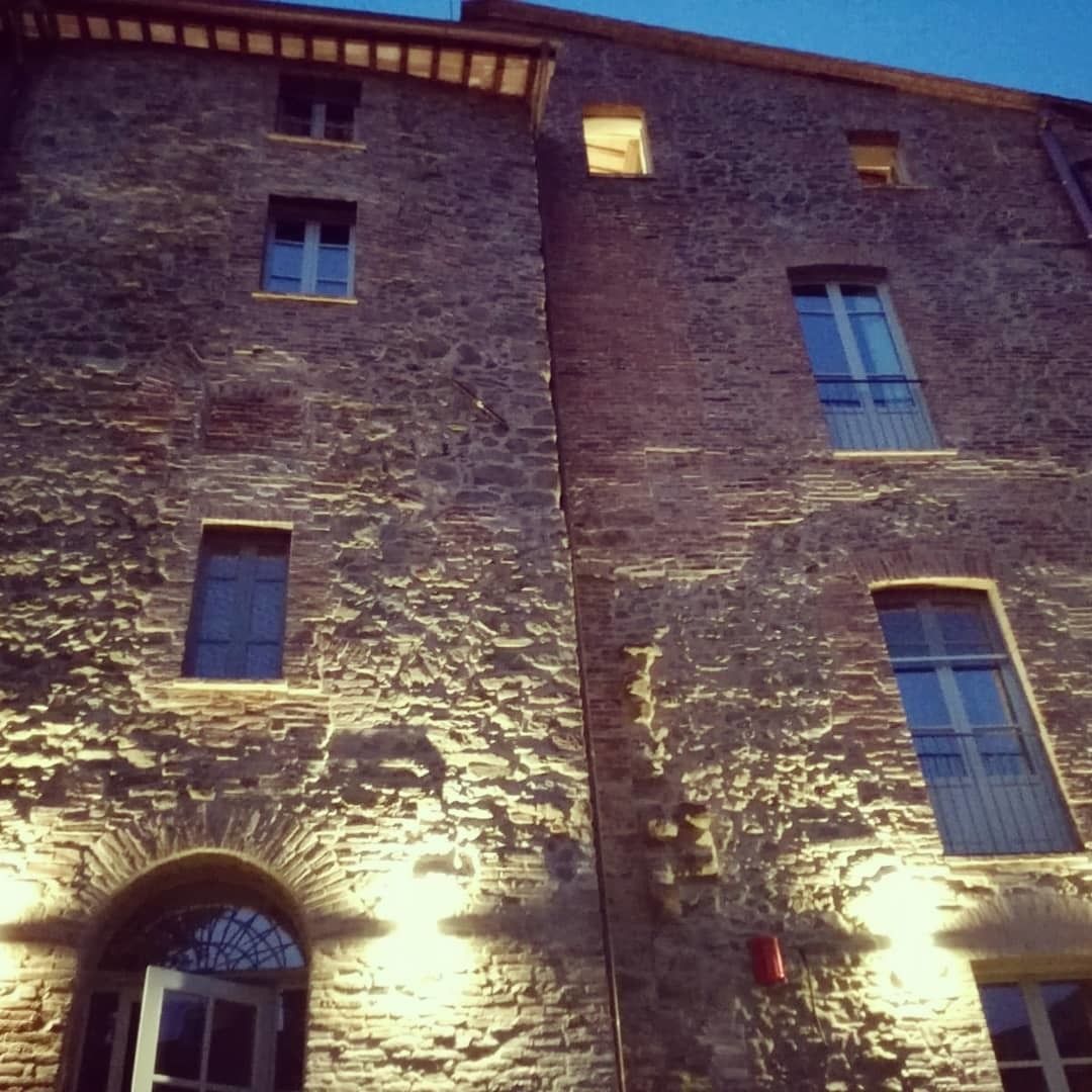 Un bâtiment en pierre doté de nombreuses fenêtres et d’une entrée en arc de cercle.