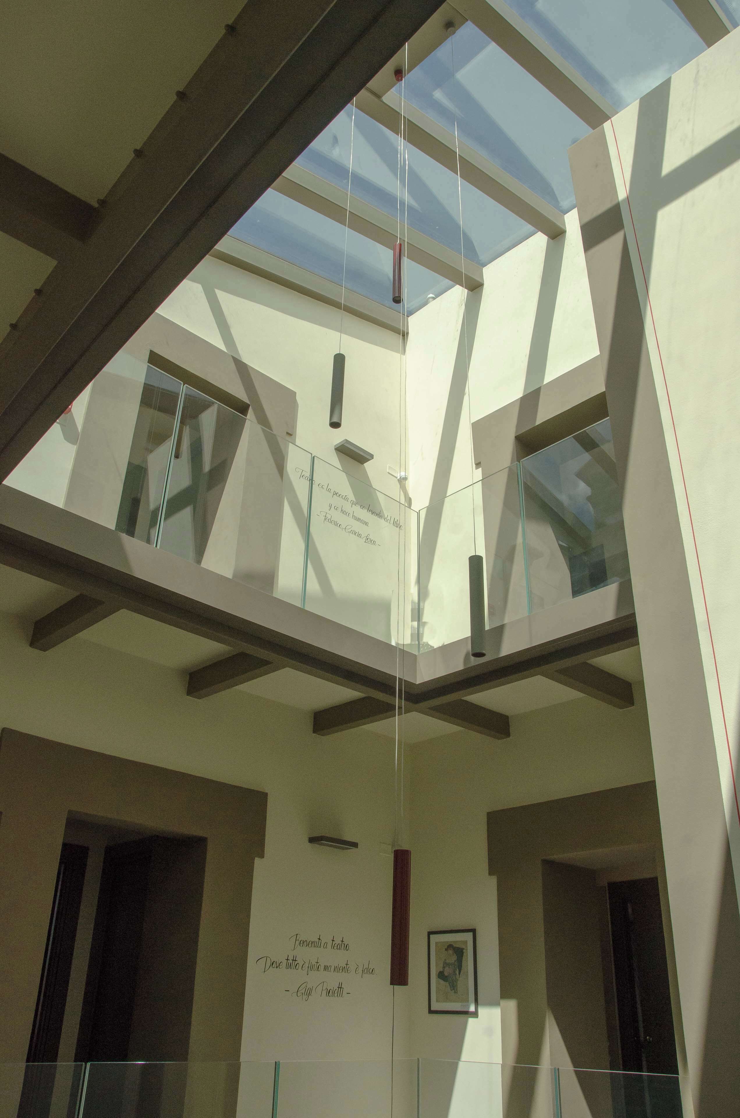 Un interior moderno con techo alto, paneles de vidrio y un entrepiso visible.