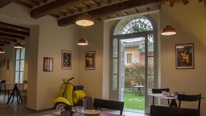 Un espace repas avec des tables préparées pour deux personnes, un scooter jaune et des œuvres d’art encadrées accrochées aux murs.