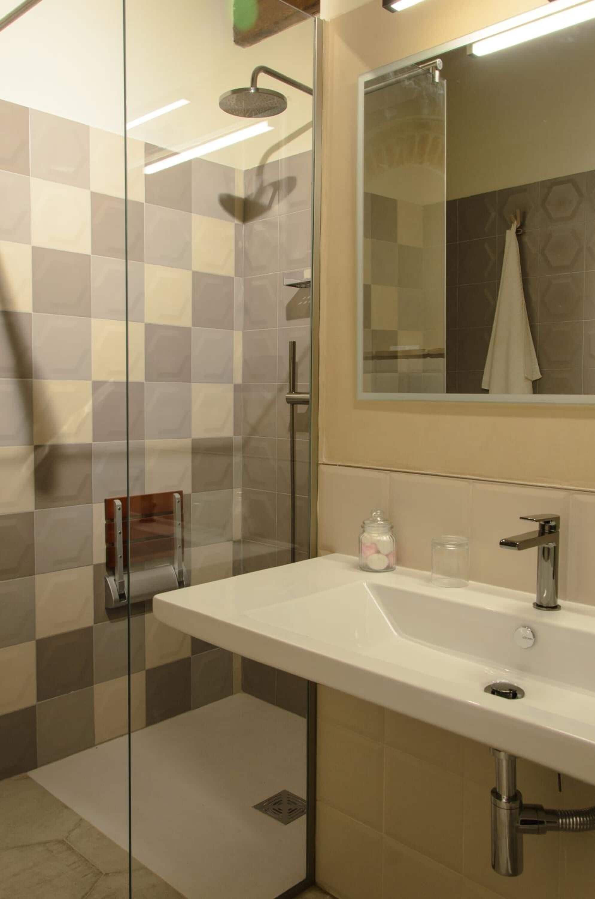 A modern bathroom with a glass-enclosed shower, a white sink, and a mirror above it.