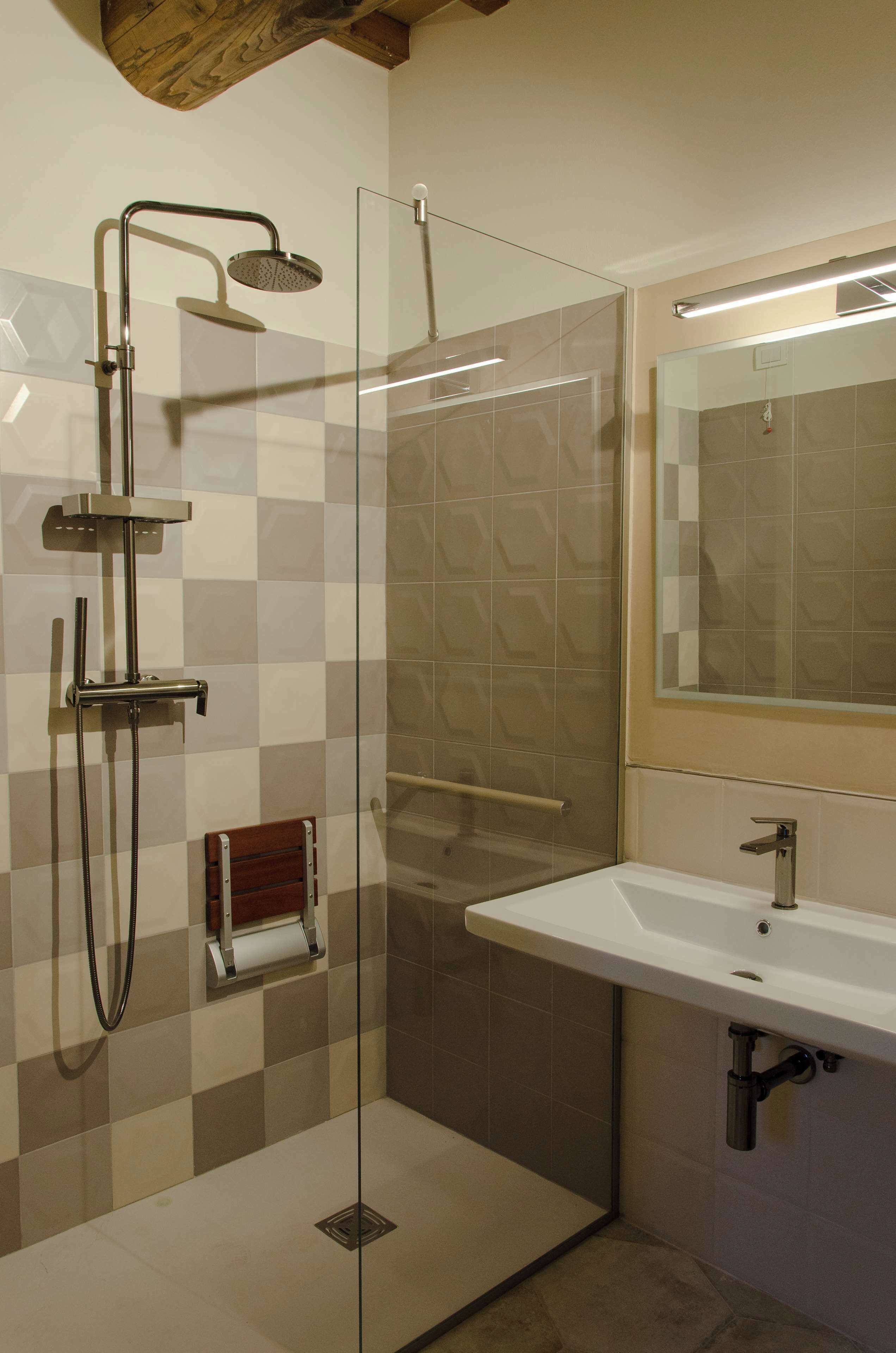 A modern bathroom with a glass-enclosed shower, a white sink, and a mirror above it.