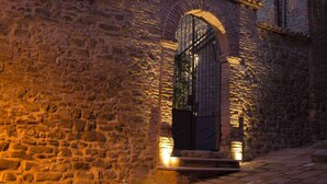 Un bâtiment en pierre doté d’une grande entrée en arc de cercle et d’un petit balcon.