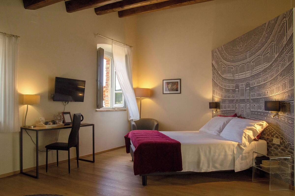 Ein Schlafzimmer mit einem Bett, einem Schreibtisch, einem Stuhl, einem Fernseher und einem Wandteppich.