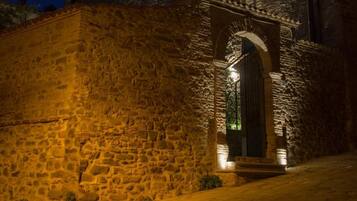 Un edificio de piedra con una entrada central en arco, iluminado por una cálida luz.