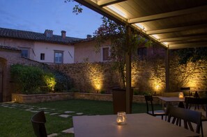 Ein Patio im Freien mit Steinmauern, einem Tisch, Stühlen und einer Kerze auf dem Tisch.