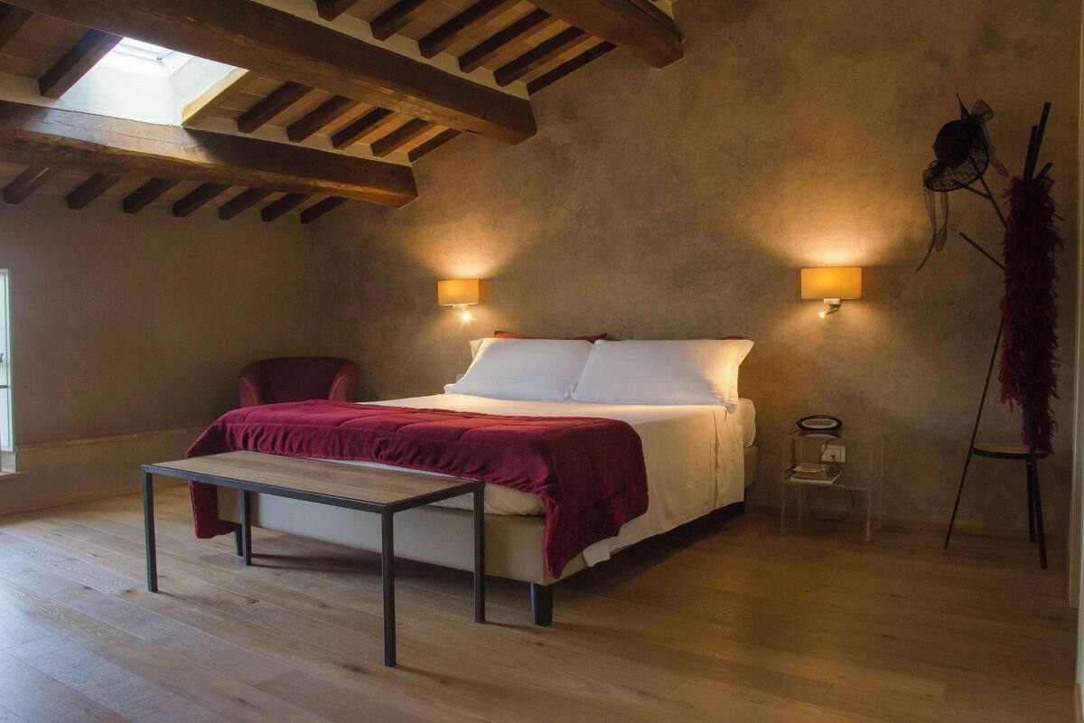 Ein Schlafzimmer mit einem Bett, einem Tisch, zwei Wandleuchten und einem Sessel.