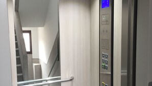 An elevator interior with a control panel, a handrail, and a glass door. - Exclusive Flats Sainte-Catherine Art (Brussels)