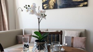 A dining table with a coffee cup, a glass, a plate, and a knife. There is a vase with white flowers and a painting on the wall. - Exclusive Flats Sainte-Catherine Art (Brussels)