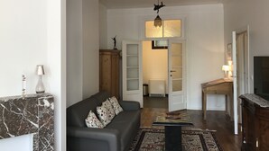 A living room with a sofa, a coffee table, a fireplace, and a television. - Exclusive Flats Sainte-Catherine Art (Brussels)
