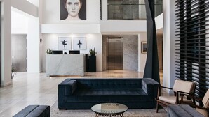 Een ruime lobby met een donkerblauwe bank, een receptiebalie en een groot abstracte sculptuur.